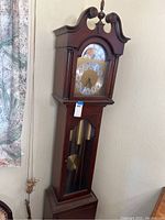 Full view of Seth Thomas grandfather clock showing the case and clock face with visible finial on top.