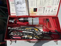 Drill, bits and manual inside red Milwaukee metal carrying case
