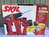 Box front showing the SKIL branded 3-tool combo kit, illustrating drill/driver, air gun inflator, and flashlight in red and black colors.