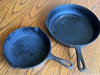 View of both cast iron skillets side by side showing overall condition and size difference.