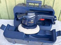 Dark blue orbital waxer with a white polishing pad inside a molded blue carrying case, showing overall condition and included case.