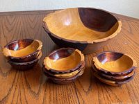 Photo showing the large salad bowl alongside eight smaller matching wooden bowls with a two-tone finish and scalloped edges.