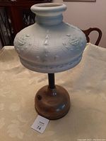 Full view of antique brass lamp with light green patterned glass shade.