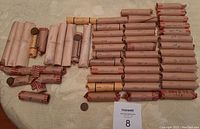 Overview of one loose penny and multiple Kraft bank wrappers on patterned tablecloth