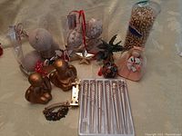 Photo showing various gold and pearl Christmas decorations including gold angel figurines, pearl-covered balls, gold bead garland in container, and gold icicle decorations in a white box.