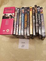 Photo of 12 DVD cases arranged standing upright on a beige surface. Titles visible are Cold Feet (series 1-5 boxed), Shetland Season 5, The Dish, Hamish Macbeth Series 1, The Summerdahl Murders Series 1, Homeland Series 1, Whitstable Pearl, The Men Who Stare at Goats, Alibi, Keeping Faith series 1, Keeping Faith series 2, and Press.