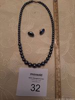 Necklace and earrings displayed against a neutral background with a measuring ruler showing necklace length.