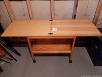 Photo of the tea cart fully extended showing wooden folding surface, lower shelf, metal handles, and roller wheels