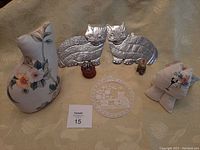 Full lot view showing fabric cat doorstop, Mexican tin cats on wooden bases, and small fabric trinket boxes on a quilted beige surface.