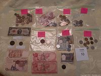 Overview of all currency in the lot displayed on a table, including coins and paper bills in bags and loose.