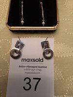 Photo showing small seed-like pearl drop earrings on fine gold chains.