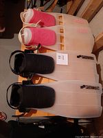 Two pairs of scuba flippers on a wooden surface, Tulsa pink pair and Sherwood black pair