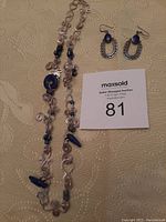 Full view of the sterling silver wire necklace with lapis lazuli stones and matching earrings laid out flat beside a paper with lot number.