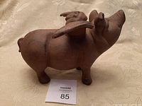 Side view of cast iron flying pig garden ornament on a beige surface.
