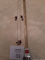 Full view of sterling silver necklace and matching earrings with a ruler for scale, displayed on light fabric background