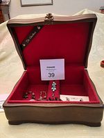 Open wooden jewelry box 'Duchess' with visibly red lining and some earrings inside.