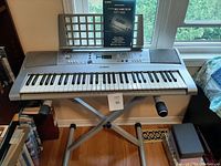 Yamaha YPT-300 keyboard on collapsible stand with manual on music rest in front of window