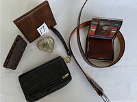 Photo showing assortment of wallets, heart-shaped belt buckle, leather belt, and a small coin or token