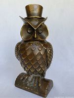 Front view of the bronze owl figurine showing detailed feathers, facial features and top hat.