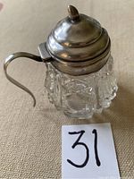Full view of the condiment server showing cut crystal body and sterling silver mounted lid and handle.