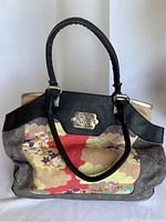 Full view of the handbag showing multicoloured floral pattern, black leather handle, and body trim.
