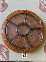 Top-down view of the circular wooden Lazy Susan with six clear sectional dividers fitted around a central circular piece.