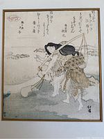 Full view of the framed Japanese woodblock print showing two figures near water, calligraphy, and a red stamp.