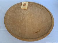 Top view of round maple wood Lazy Susan with original Maple Tree Craft tag attached, showing natural wood grain and shallow raised edge.