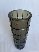 Full frontal view of tall cylindrical smoky gray cut crystal vase with geometric grid cut pattern.