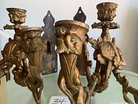 Close-up photo showing detailed brass cast metal work on the pair of antique gold tone wall candle sconces, highlighting the swivel candle mounts and aged patina.