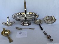 View of all seven vintage silver and silver-plated items in the lot arranged on a flat surface.