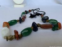 Full view of tribal necklace laid flat showing multi-colored semi-precious stone beads and brass spacers.