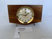 Front and angled view of rectangular teak wind-up alarm clock by Westclox with brass bezel and white dial.