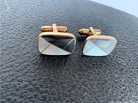 Pair of rectangular cufflinks showing diagonal mother of pearl and abalone inlays on a black surface