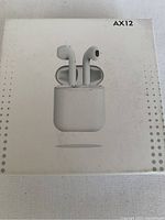 Front of sealed box showing image of white wireless ear phones and box labeled AX12