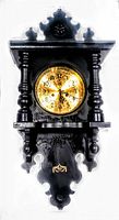 Full view of the antique dark stained hand carved wooden wall mount clock with ornate accents and gold-tone face.