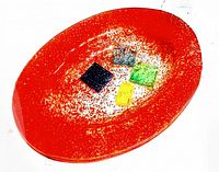 Top angled view of the orange mid century art glass trinket dish with colored square insets in the center, showing texture and colors.