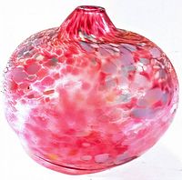 Side angle view showing rounded bulbous shape and multicolor mottled glass with dominant red hues and accents of gray, white, yellow.