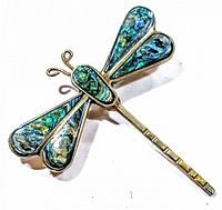 Close-up photo of vintage dragonfly brooch or pendant showcasing iridescent abalone shell in wings and body, with gold-toned metal framing and antennae.