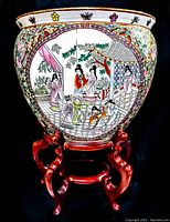 Front view of the large ceramic koi fish bowl on wooden stand showing hand-painted figures and floral borders.