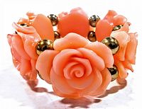 Close-up front view of the bracelet showing detailed peach floral elements resembling roses with brass beads between each flower.