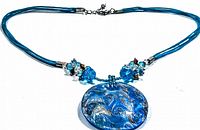 Front view of vintage lucite necklace showing round blue pendant with embedded silver swirls and blue cord with beads