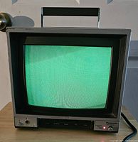 Front view of the Panasonic color video monitor powered on, showing green screen and front controls.
