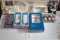 Photo of all packaged items showing Taylor Bath Set in white (without towel ring and hardware), two Aviva soap dispensers, Taymor and Pegasus towel bars, and Eiffel Tower shower hooks