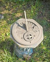 Overhead view of sundial showing dial and gnomon against grass