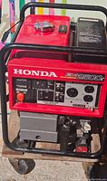 Front view showing red Honda EM2500 control panel with outlets, circuit breaker and steel frame.