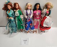 Front view of five International Barbie dolls in colorful traditional dresses, standing upright against a neutral background.