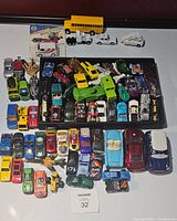 Top view of the lot showing various diecast cars including a yellow school bus, ambulance, and a mix of race and sports cars in various colors and brands.