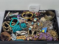 Top-down photo of entire assortment of costume jewelry showing multiple colors and styles including bracelets, necklaces, and brooches.