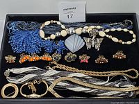 Full view of the jewelry lot arranged on a tray showing multiple necklaces, brooch pins, earrings, bracelets, a ring, and hair clips in various colors and materials.